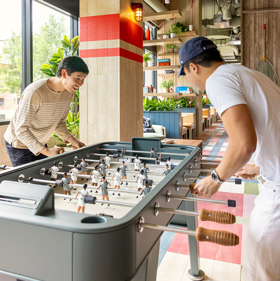 Two friends playing at a foosball table